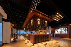 a restaurant with a bar with chairs and tables at Moxy Nanjing Jiangning in Nanjing