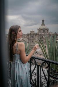 a woman standing on a balcony holding a glass of wine at Zócalo Central in Mexico City