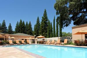 a pool at a hotel with chairs and umbrellas at Courtyard Sacramento Airport Natomas in Sacramento