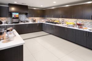 a large kitchen with dark wood cabinets and white floors at Residence Inn by Marriott Houston Pasadena in Pasadena