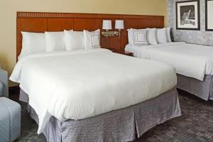 Habitación de hotel con 2 camas con sábanas blancas en Courtyard Aberdeen at Ripken Stadium, en Aberdeen