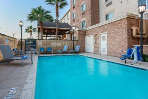 a swimming pool with chairs and a building at TownePlace Suites El Centro in El Centro