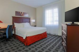 um quarto de hotel com uma cama, uma secretária e uma televisão em TownePlace Suites El Centro em El Centro