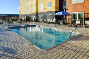 a swimming pool with chairs and an umbrella next to a building at Fairfield Inn & Suites by Marriott Martinsburg in Martinsburg