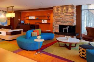 a living room with blue chairs and a fireplace at Fairfield Inn & Suites by Marriott Springfield Northampton/Amherst in Northampton