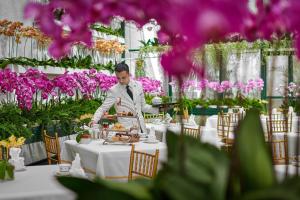 Ein Mann, der Essen an einem Tisch in einem Restaurant serviert. in der Unterkunft The Majestic Hotel Kuala Lumpur, Autograph Collection in Kuala Lumpur