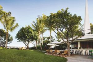 un complexe avec des tables, des chaises et des palmiers dans l'établissement The Miami Beach EDITION, à Miami Beach