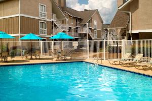 a pool with chairs and umbrellas next to a building at Residence Inn by Marriott Atlanta Cumberland/Galleria in Atlanta