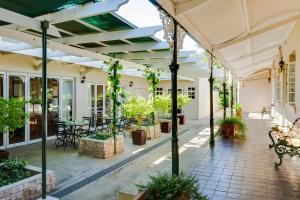 un patio al aire libre con mesas, bancos y plantas en Protea Hotel by Marriott Dorpshuis & Spa Stellenbosch, en Stellenbosch