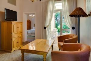 uma sala de estar com uma mesa e cadeiras e uma televisão em Protea Hotel by Marriott Dorpshuis & Spa Stellenbosch em Stellenbosch