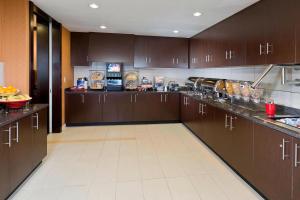 a large kitchen with brown cabinets and a white tile floor at Residence Inn Bismarck North in Bismarck