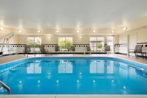 a pool in a hotel with chairs and tables at Fairfield Inn Kankakee Bourbonnais in Bourbonnais