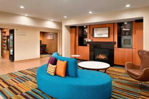 a living room with a blue couch and a fireplace at Fairfield Inn & Suites Hartford Manchester in Manchester