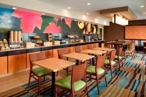 a restaurant with wooden tables and green chairs at Fairfield Inn & Suites Hartford Manchester in Manchester