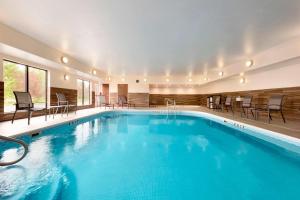 uma piscina num hotel com cadeiras e mesas em Fairfield Inn & Suites Hartford Manchester em Manchester