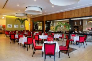 a restaurant with white tables and red chairs at Aguascalientes Marriott Hotel in Aguascalientes