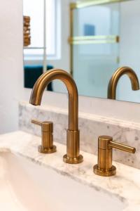 a bathroom sink with two faucets and a mirror at Modern Beach Oasis in San Diego