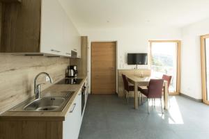 a kitchen with a sink and a table with chairs at Appartements Martinsheim in Tirolo