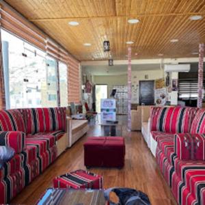 Petra cabin Roof top hostel في وادي موسى: غرفة معيشة مع كنب احمر وطاولة