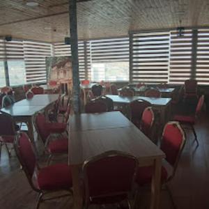 a dining room with tables and chairs and windows at Petra cabin Roof top hostel in Wadi Musa