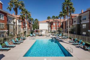 a swimming pool with chairs and palm trees and buildings at Residence Inn by Marriott Las Vegas Henderson/Green Valley in Las Vegas