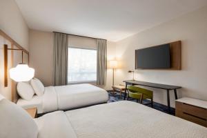 a hotel room with two beds and a desk and a television at Fairfield by Marriott Inn & Suites Bonita Springs in Bonita Springs