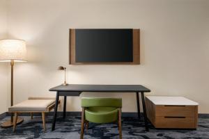 a desk with a chair and a television on a wall at Fairfield by Marriott Inn & Suites Bonita Springs in Bonita Springs