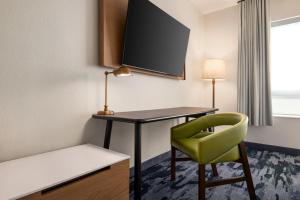 a room with a desk and a green chair at Fairfield by Marriott Inn & Suites Bonita Springs in Bonita Springs