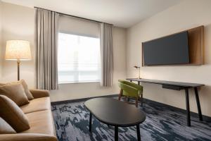 a hotel room with a couch and a table and a tv at Fairfield by Marriott Inn & Suites Bonita Springs in Bonita Springs