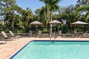 a swimming pool with chairs and tables and umbrellas at Fairfield by Marriott Inn & Suites Bonita Springs in Bonita Springs