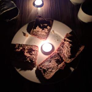 a plate with three pieces of cake and a candle at Petra cabin Roof top hostel in Wadi Musa