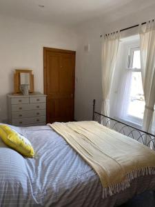 a bedroom with a bed with a yellow pillow and a window at Boston House- Historic house situated in beautiful market town in Duns