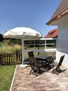 a table and chairs under an umbrella on a patio at "Kleine 4" Idyllisches TinyHouse an der Nordsee in Norden