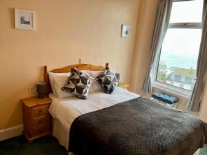 um quarto com uma cama com almofadas e uma janela em Ocean View em Ilfracombe