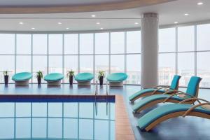 - une piscine avec des chaises bleues dans une grande pièce dotée de fenêtres dans l'établissement Residence Inn by Marriott Jazan, à Jazan