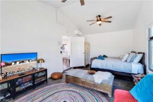 a bedroom with a bed and a tv and a couch at Cozy Fresh Desert Hideaway, 5 mins to Joshua Tree in Twentynine Palms