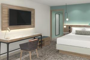 a bedroom with a bed and a desk with a tv at Courtyard by Marriott Curacao in Willemstad