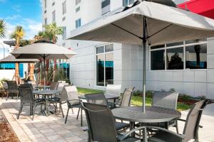 an outdoor patio with tables and chairs and umbrellas at Fairfield Inn & Suites by Marriott Daytona Beach Speedway/Airport in Daytona Beach
