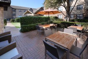 un patio con mesas, sillas y una sombrilla en Residence Inn by Marriott Dallas Plano/Legacy, en Plano