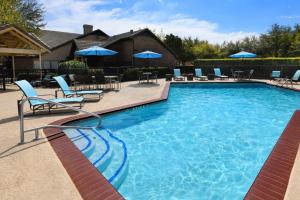 a swimming pool with chairs and blue umbrellas at Residence Inn by Marriott Dallas Plano/Legacy in Plano