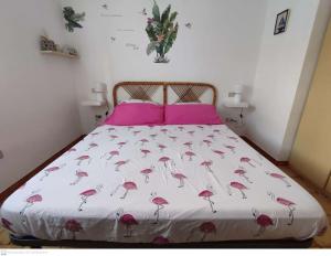 Una cama con una colcha rosa con flamencos. en Casa Flamingo House en San Teodoro