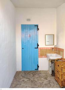 porta blu in bagno con lavandino di Casa Flamingo House a San Teodoro