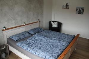 1 dormitorio con 1 cama con edredón azul y silla en Ferienwohnung Zur Alten Ziegelei, en Bad Emstal