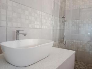 y baño blanco con bañera y ducha. en Nakhah Guesthouse - Double Room en Witbank