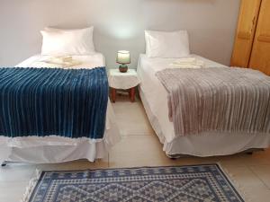 Habitación con 2 camas y mesa con lámpara. en Nakhah Guesthouse - Double Room en Witbank