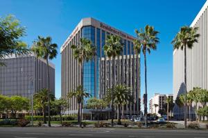 un grand bâtiment avec des palmiers devant lui dans l'établissement Residence Inn by Marriott Los Angeles LAX/Century Boulevard, à Los Angeles