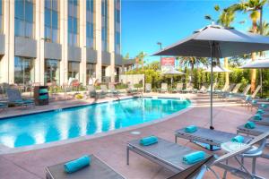 a pool at a hotel with chairs and an umbrella at Residence Inn by Marriott Los Angeles LAX/Century Boulevard in Los Angeles