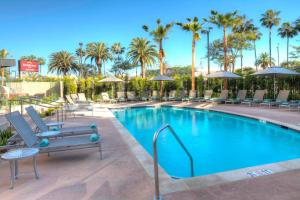 a pool at a hotel with chairs and palm trees at Residence Inn by Marriott Los Angeles LAX/Century Boulevard in Los Angeles