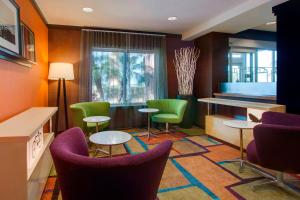 Fairfield Inn & Suites by Marriott Clermont في كليرمون: غرفه فيها كراسي وطاولات وبيانو