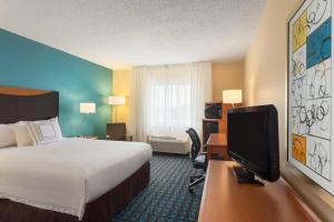 a hotel room with a bed and a flat screen tv at Fairfield Inn & Suites by Marriott Norman in Norman